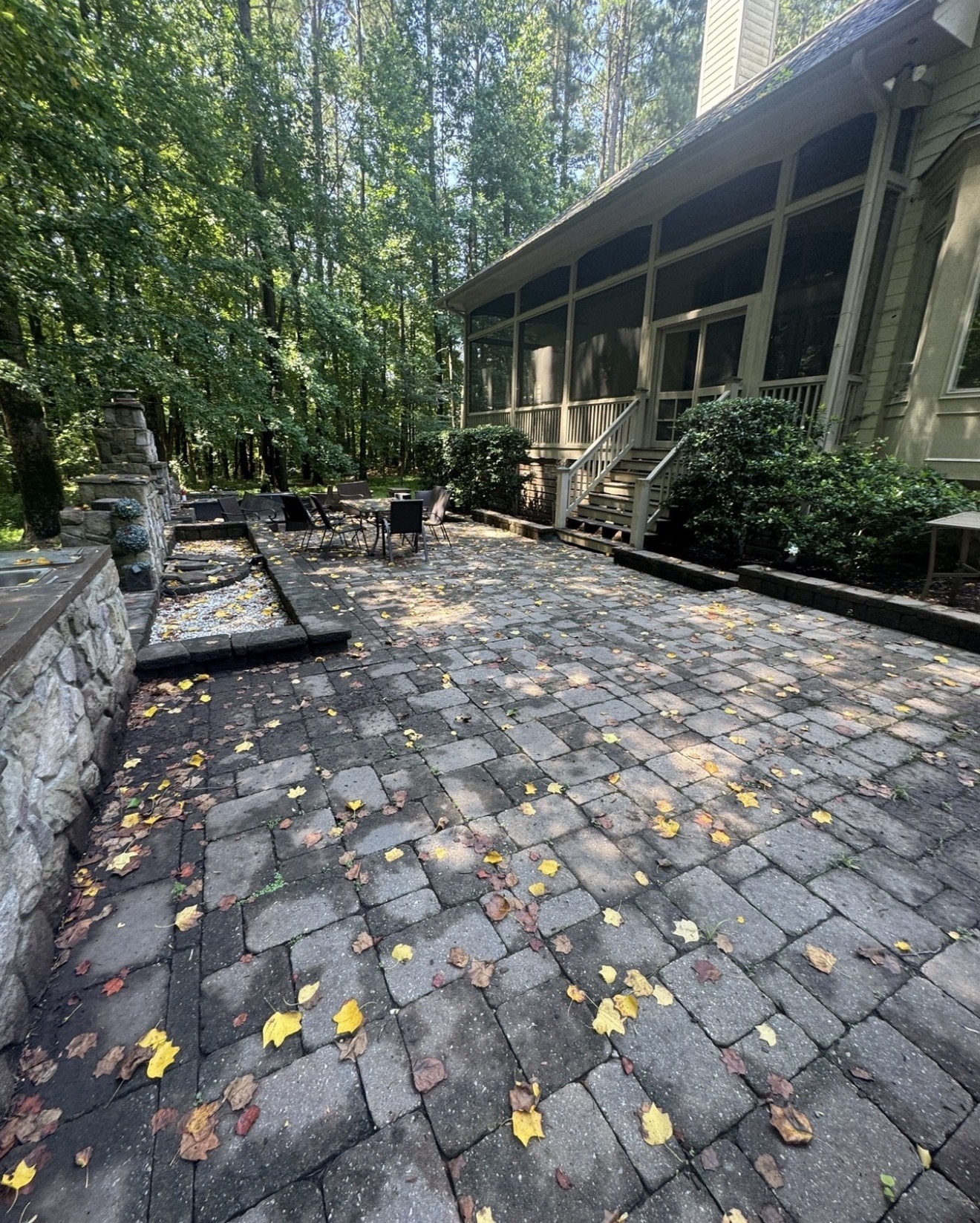 Dirty brick paver patio with leaves and grime before pressure washing