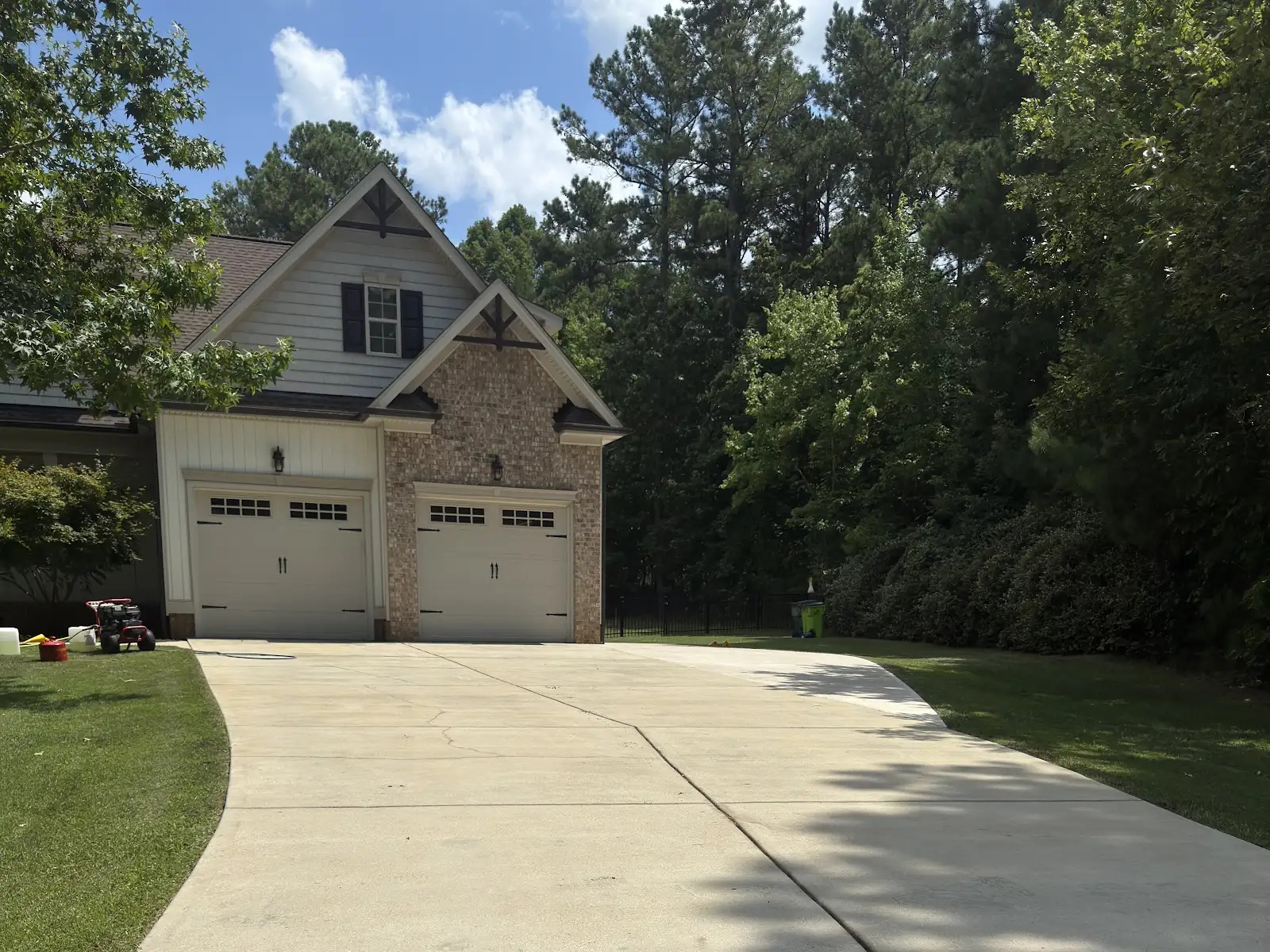 Concrete driveway being pressure washed in White Oak Garner NC showing red clay and algae removal